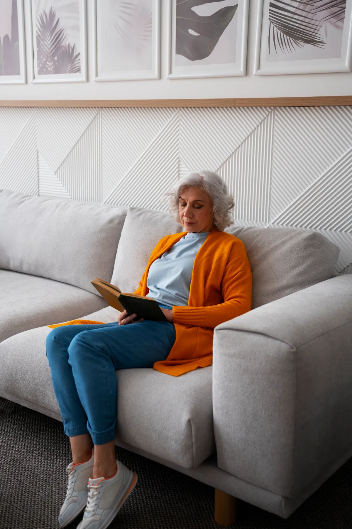 Senhora lendo com tranquilidade no sofá de casa