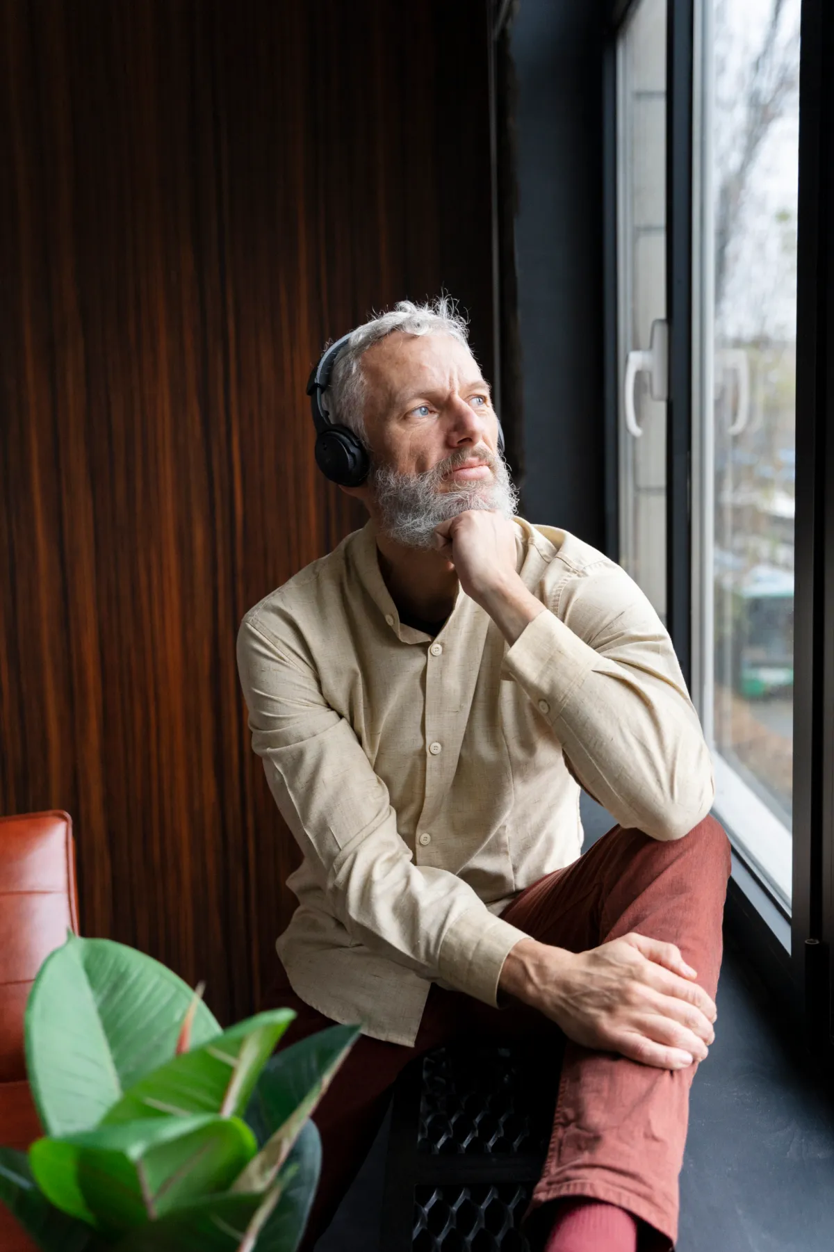 Senhor ouvindo música com fones, olhando pela janela